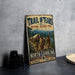 a vintage-style metal sign for the Trail of Tears National Historic Trail, depicting a group of people in traditional clothing walking along a path through a mountainous landscape.