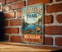 A vintage-style metal sign with the text "VOYAGEURS TRAIL" and "WATERWAYS WILDERNESS HISTORY MICHIGAN EXPLORE THE LEGACY" is displayed on a brick wall.
