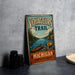 A vintage-style metal sign advertising the Michigan Voyageurs Trail, featuring a canoe and a scenic landscape.