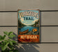 A vintage-style metal sign on a wall, featuring a canoe and a scenic landscape with a lake and mountains.