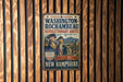 A vintage-style metal sign with the text "WASHINGTON-ROCCHAMBEAU REVOLUTIONARY ROUTE" and "A PART OF ALLIANCE A LEGACY OF FREEDOM" is displayed on a wooden wall.