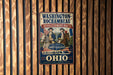A vintage-style metal sign with the text "WASHINGTON-ROCKAMBEAU REVOLUTIONARY ROUTE" and images of two men on horseback, along with the text "TRADING THE BONUS LIBERTY & ALLIANCE" and "OHIO" at the bottom.