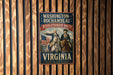A vintage-style metal sign with the text "WASHINGTON-ROCCHAMBEAU REVOLUTIONARY ROUTE VIRGINIA" and an illustration of two men on horseback, one of whom is holding a flag.
