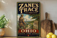A vintage-style sign for "Zane's Trace" is displayed on a wooden shelf, featuring a man in a historical outfit and a scenic landscape.