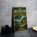 A vintage-style sign for Marion State Park in Ohio, featuring a scenic landscape with a lake and trees, is displayed on a gray concrete surface.