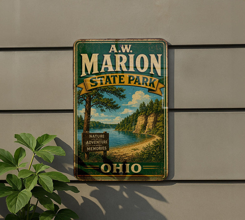 A vintage metal sign for A.W. Marion State Park, featuring a scenic landscape with a lake and mountains, is displayed on a wall next to a plant.