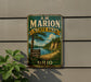A vintage metal sign for A.W. Marion State Park, featuring a scenic landscape with a lake and mountains, is displayed on a wall next to a plant.