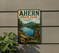 A vintage-style metal sign for Ahern State Park in New Hampshire, featuring a scenic landscape with a lake, mountains, and pine trees.