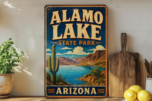 A vintage-style sign for Alamo Lake State Park in Arizona, featuring a desert landscape with a cactus and a lake.