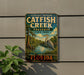 A vintage-style metal sign for Catfish Creek Preserve, Florida, featuring a large bird and a serene landscape.
