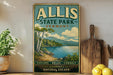 A vintage-style sign for Allis State Park in Vermont, featuring a scenic landscape with a lake and mountains.