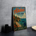 A vintage metal sign for Aloha State Park, Michigan, featuring a scenic landscape with a beach, mountains, and pine trees.