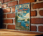 A vintage-style metal sign for Alum Creek State Park in Ohio, featuring a scenic illustration of a lake with a sailboat, surrounded by nature and outdoor activities.