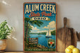A vintage-style sign for Alum Creek State Park in Ohio, featuring a scenic illustration of a lake with a sailboat, surrounded by trees and mountains.