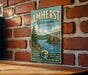 A vintage-style metal sign for Amherst State Park in New York, featuring a scenic landscape with a lake and mountains.