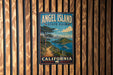 A vintage-style metal sign for Angel Island State Park in California, featuring a scenic landscape with a path leading to the park.