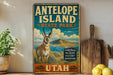 A vintage-style sign for Antelope Island State Park in Utah, featuring an illustration of a mountain range and a gazelle.