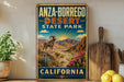 A vintage-style sign for Anza-Borrego Desert State Park in California, featuring a desert landscape with a ram and cacti.