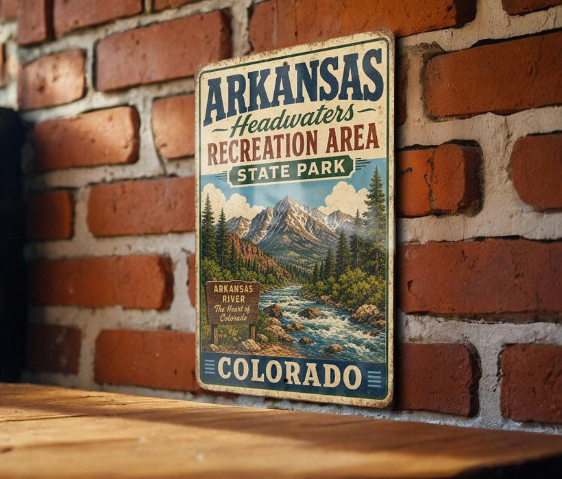 A vintage metal sign for Arkansas Headwaters Recreation Area in Colorado, featuring a scenic mountain landscape with a river and pine trees.