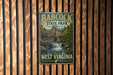A vintage-style metal sign for Babcock State Park in West Virginia, featuring a scenic illustration of a waterfall and a wooden mill.