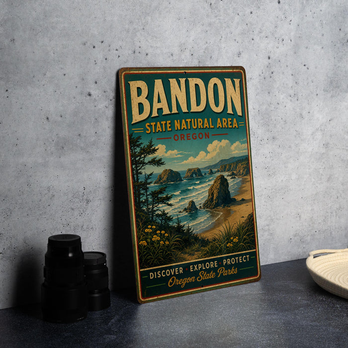 A vintage-style metal sign for Bandon State Natural Area in Oregon, featuring a scenic landscape with mountains, trees, and a beach.