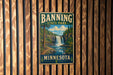 A vintage-style metal sign for Banning State Park in Minnesota, featuring a waterfall and forest landscape.