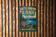 A vintage metal sign for Battle Ground Lake State Park in Washington, featuring a scenic image of the lake and mountains.