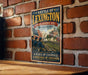 A vintage metal sign with a historical illustration of a battle scene, mounted on a brick wall.