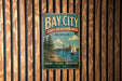 A vintage metal sign for Bay City State Recreation Area in Michigan, featuring a scenic illustration of a sailboat on a lake surrounded by trees.
