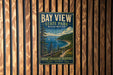 A vintage-style metal sign for Bay View State Park in Washington, featuring a scenic landscape with a lake, mountains, and pine trees.