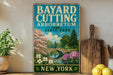 A vintage-style sign for Bayard Cutting Arboretum in New York, featuring a scenic landscape with a bridge, trees, and flowers.