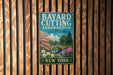 A vintage metal sign for Bayard Cutting Arboretum in New York, featuring a scenic landscape with a bridge and blooming trees.