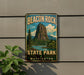 A vintage-style metal sign for Beacon Rock State Park in Washington, featuring a scenic mountain landscape with a lake and pine trees.