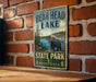 A vintage metal sign for Bear Head Lake State Park in Minnesota, featuring a bear and a scenic landscape.
