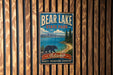 A vintage metal sign for Bear Lake State Park in Idaho, featuring a bear walking along a beach and mountains in the background.
