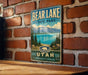 A vintage metal sign for Bear Lake State Park in Utah, featuring a scenic landscape with mountains, pine trees, and a lake.