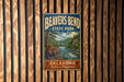A vintage metal sign for Beaver Bend State Park in Oklahoma, featuring an illustration of a beaver in a river surrounded by trees and mountains.