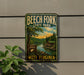 A vintage-style metal sign for Beech Fork State Park in West Virginia, featuring a scenic landscape with a river, trees, and a cabin.