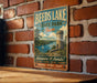 A vintage-style metal sign for Beeds Lake State Park in Iowa, featuring a castle, a lake, and a sailboat, mounted on a brick wall.