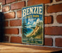 A vintage-style metal sign for Benzie State Park in Michigan, featuring a scenic landscape with a beach, mountains, and pine trees.