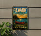 A vintage-style metal sign for Bewabic State Park, featuring a canoe and a scenic landscape, is displayed on a wall next to a plant.