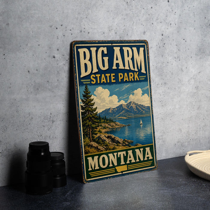 A vintage-style metal sign for Big Arm State Park in Montana, featuring a scenic landscape with mountains, a lake, and a sailboat.