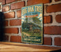 A vintage-style metal sign for Big Oak Tree State Park in Missouri, featuring an illustration of a large oak tree and a sign that reads "Home of the Big Oak Tree".