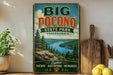 a vintage-style sign for Big Pocono State Park in Pennsylvania, with a scenic landscape of a lake and mountains in the background.