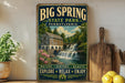 A vintage-style sign for Big Spring State Park in Pennsylvania, featuring a scenic image of a waterfall and a house.