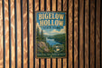 A vintage metal sign for Bigelow Hollow State Park, featuring a scenic landscape with a lake and mountains, mounted on a wooden wall.