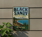 A vintage-style metal sign for Black Sandy State Park in Montana, featuring a scenic landscape with mountains, pine trees, and a lake.