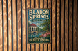 A vintage metal sign for Bl Donkey Springs State Park in Alabama, featuring a scenic image of the park and a fountain.
