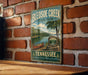 A vintage-style metal sign for Tennessee State Park, specifically Bledsoe Creek, is displayed on a brick wall.