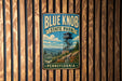 A vintage metal sign for Blue Knob State Park in Pennsylvania, featuring a scenic illustration of a lookout tower and mountains.